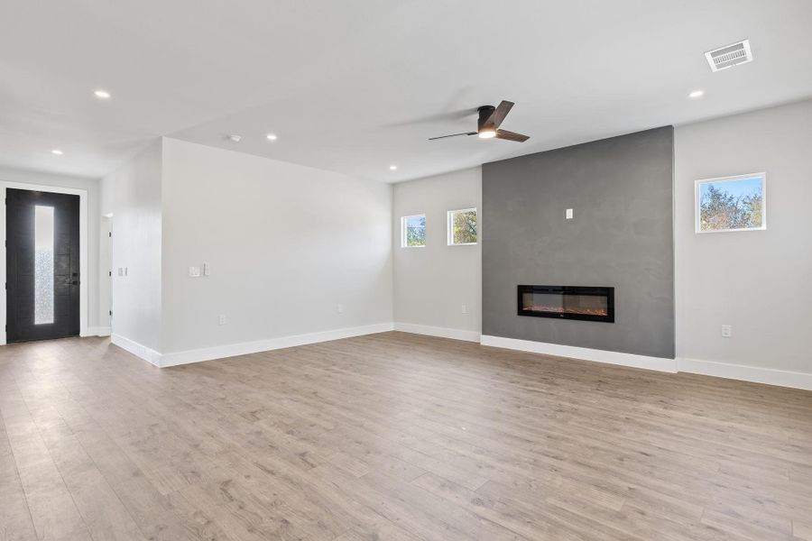 Unfurnished living room featuring light wood finished floors, recessed lighting, a large fireplace, and ceiling fan