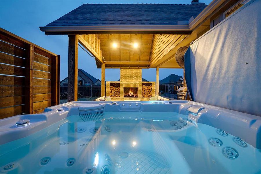 View of pool featuring an outdoor brick fireplace and a hot tub