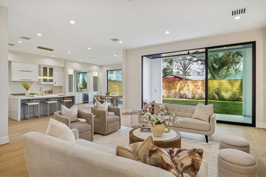A sweeping wall of sliding glass doors brings in abundant light and creates a fluid connection to the outdoors, while the oak flooring extends into the kitchen for a cohesive, open-concept design.