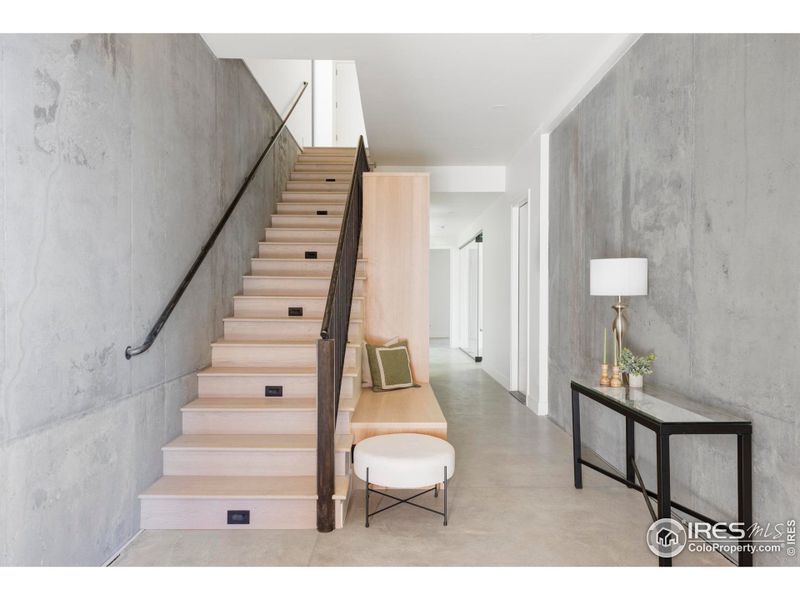 The polished concrete porch opens on the lower level, where a large foyer boasts bench seating and a row of mudroom storage. The polished concrete porch opens on the lower level, where a large foyer boasts bench seating and a row of mudroom storage.