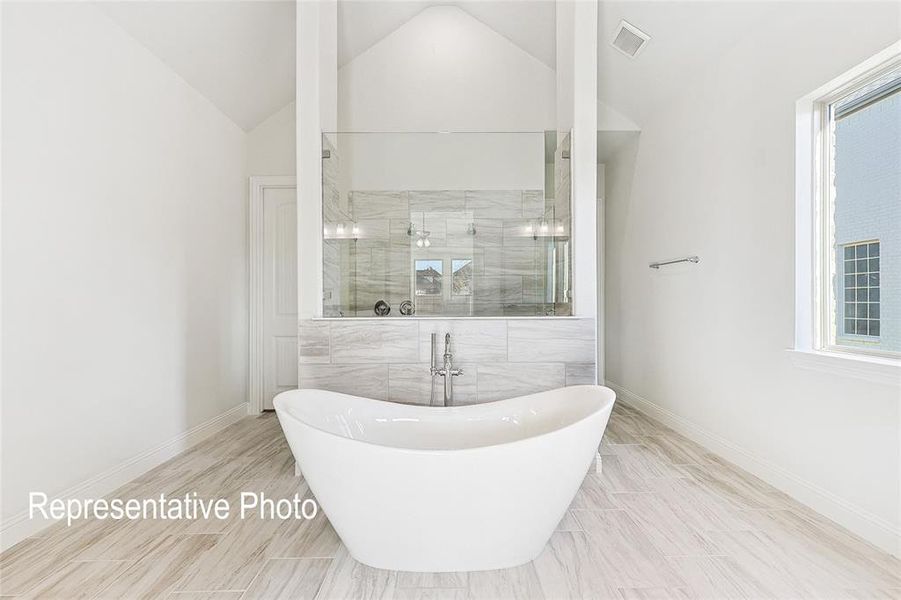 Bathroom featuring plus walk in shower, lofted ceiling, a healthy amount of sunlight, and tile patterned floors