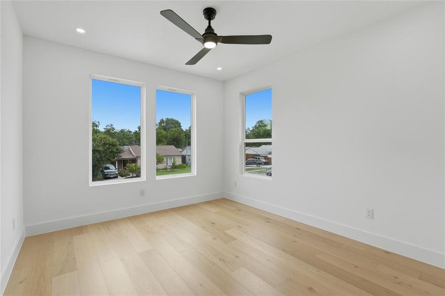 Bright interior space featuring light wood-finish flooring and a contemporary black ceiling fan with integrated lighting Bright interior space featuring light wood-finish flooring and a contemporary black ceiling fan with integrated lighting