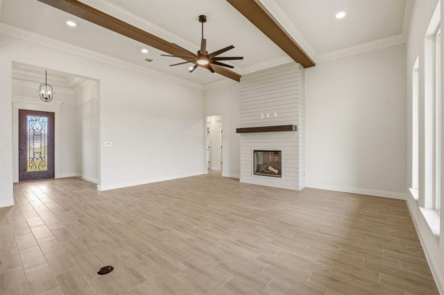 Unfurnished living room with a ceiling fan, wood finish floors, beam ceiling, a fireplace, and recessed lighting