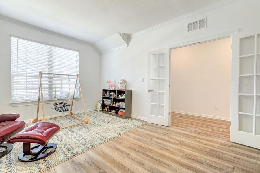 Living area with crown molding, wood finished floors, plenty of natural light, and french doors