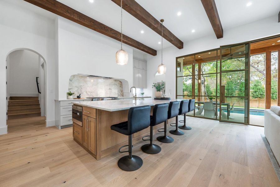 Kitchen featuring brown cabinetry, hanging light fixtures, a breakfast bar area, white cabinets, and recessed lighting Kitchen featuring brown cabinetry, hanging light fixtures, a breakfast bar area, white cabinets, and recessed lighting