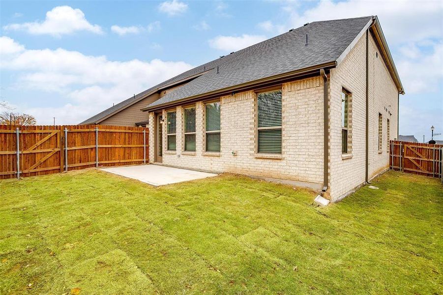 Rear view of property with a yard, a patio, and brick siding