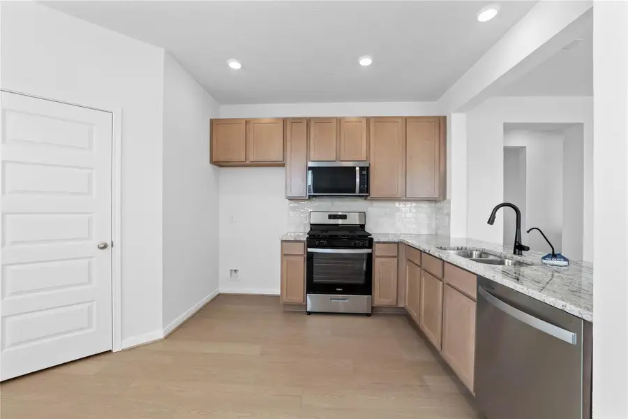 Efficiently designed kitchen maximizes every inch of space, with Woodmont Dakota cabinetry in Barley, Whirlpool stainless steel appliances, and granite countertops. The perfect functional hub for daily cooking. Efficiently designed kitchen maximizes every inch of space, with Woodmont Dakota cabinetry in Barley, Whirlpool stainless steel appliances, and granite countertops. The perfect functional hub for daily cooking.