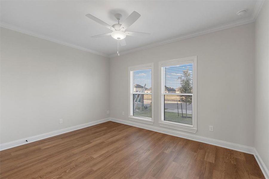 Empty room featuring crown molding, wood finished floors, and a ceiling fan Empty room featuring crown molding, wood finished floors, and a ceiling fan