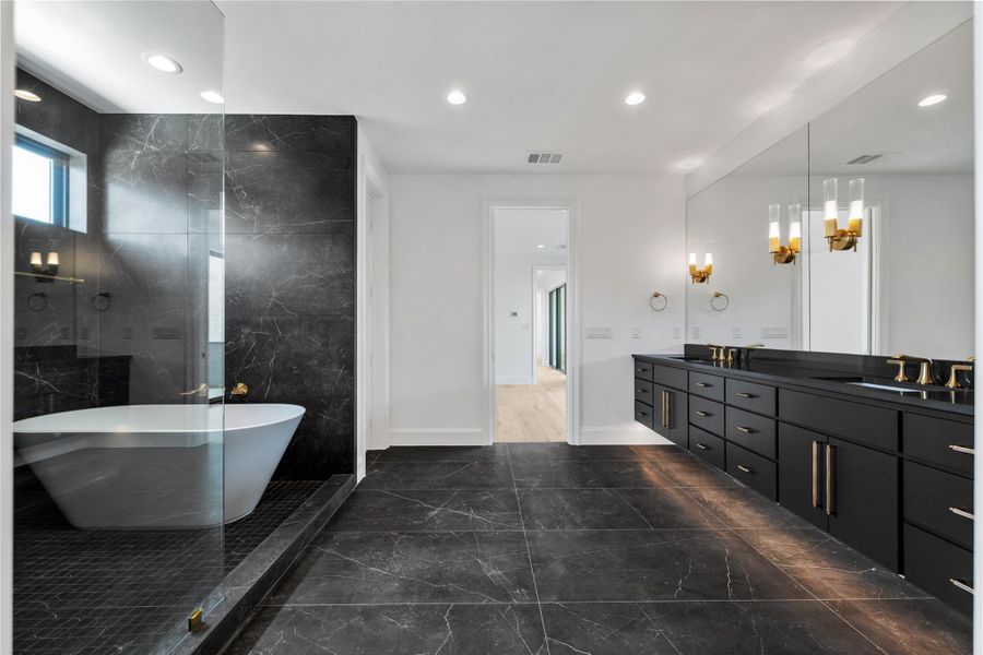 Bathroom featuring double vanity, dark marble finish floors, a soaking tub, a marble finish shower, and a chandelier