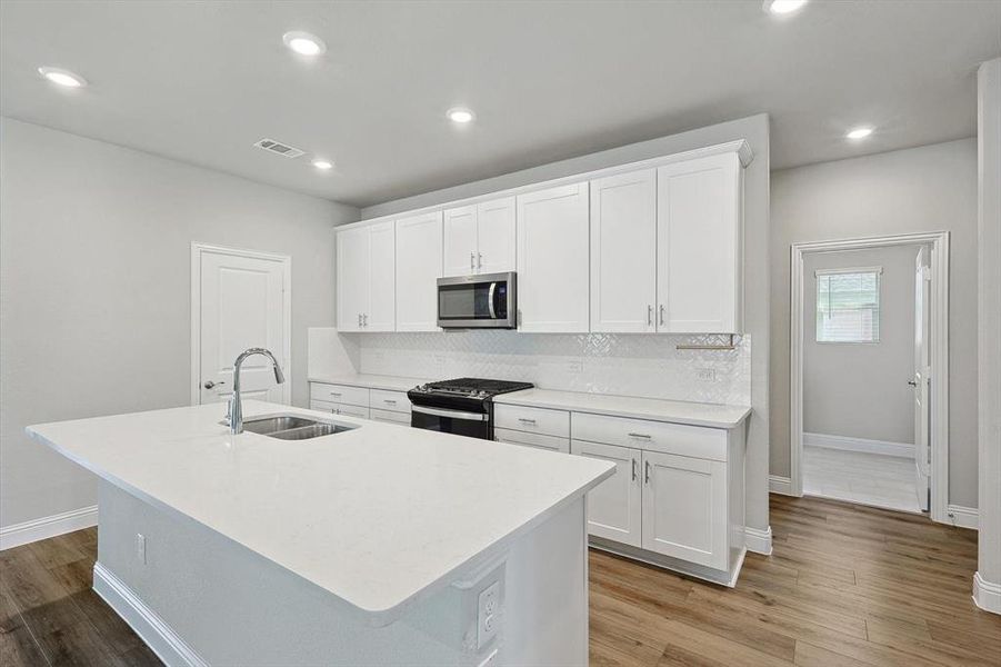 Kitchen with appliances with stainless steel finishes, white cabinetry, sink, and backsplash