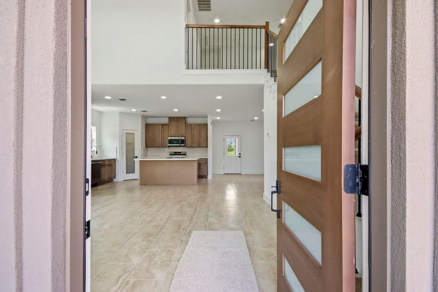 Step into a bright, open-concept living area featuring a modern kitchen with sleek cabinetry and a large island, seamlessly flowing into the spacious living room with high ceilings and abundant natural light.