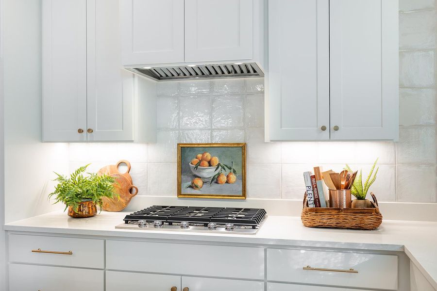 Kitchen featuring backsplash, white cabinets, extractor fan, and stainless steel gas cooktop