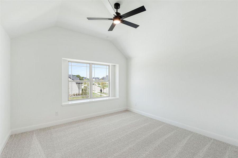 Empty bedroom with vaulted ceiling, black ceiling fan, carpet flooring, and a single window with neighborhood view Empty bedroom with vaulted ceiling, black ceiling fan, carpet flooring, and a single window with neighborhood view