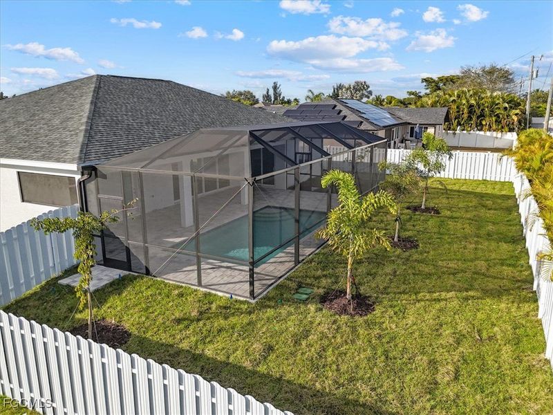 Rear view of house with a fenced backyard, a sunroom, a lanai, and roof with shingles