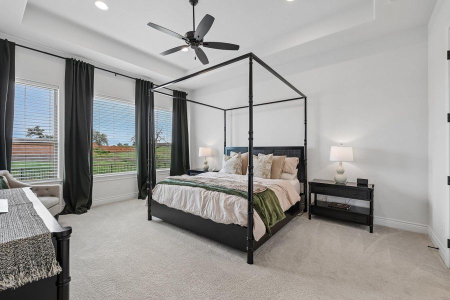 Bedroom featuring light-toned carpet flooring, white walls, and a tray ceiling with recessed lighting