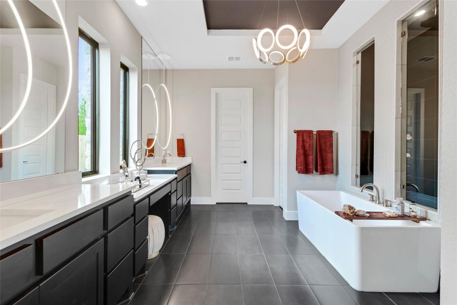 Full bathroom featuring a freestanding bath, double vanity, a tray ceiling, tile patterned floors, and a tile shower Full bathroom featuring a freestanding bath, double vanity, a tray ceiling, tile patterned floors, and a tile shower