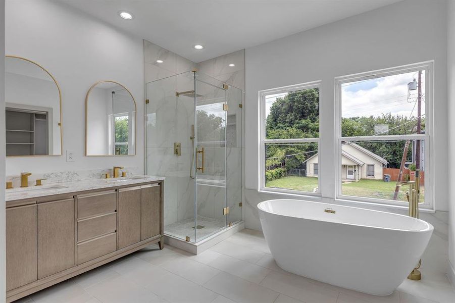 Bathroom with a marble finish shower, a freestanding tub, double vanity, recessed lighting, and tile patterned floors Bathroom with a marble finish shower, a freestanding tub, double vanity, recessed lighting, and tile patterned floors