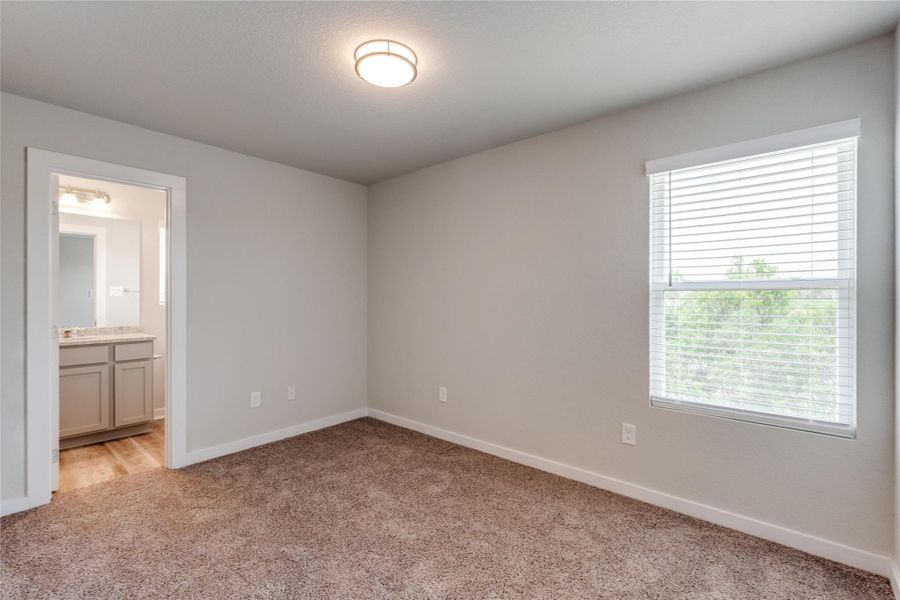 Unfurnished bedroom with light colored carpet and ensuite bathroom Unfurnished bedroom with light colored carpet and ensuite bathroom