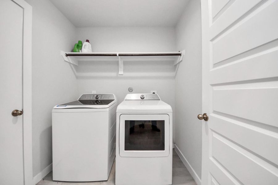 Dedicated laundry room with washer and dryer connections and an upper shelf for convenient storage.