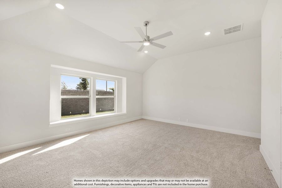 Empty bedroom with vaulted ceiling, ceiling fan, carpet flooring, and large window with backyard view Empty bedroom with vaulted ceiling, ceiling fan, carpet flooring, and large window with backyard view