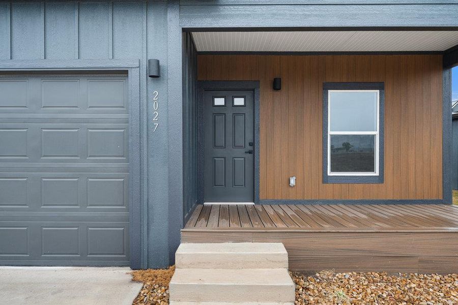 View of exterior entry featuring a garage and covered porch