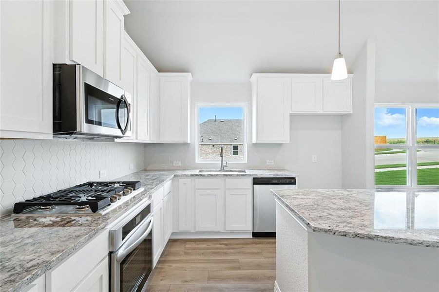 Kitchen with stainless steel appliances, white cabinets, healthy amount of natural light, and light wood finished floors