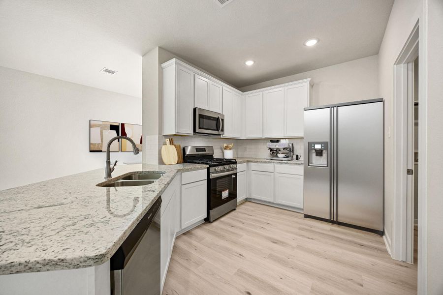 This bright and modern chef's kitchen is both stylish and functional. It features abundant white shaker-style cabinetry with chrome hardware, clean light granite countertops, stainless steel appliances, and a crisp white backsplash. *Virtually Staged This bright and modern chef's kitchen is both stylish and functional. It features abundant white shaker-style cabinetry with chrome hardware, clean light granite countertops, stainless steel appliances, and a crisp white backsplash. *Virtually Staged