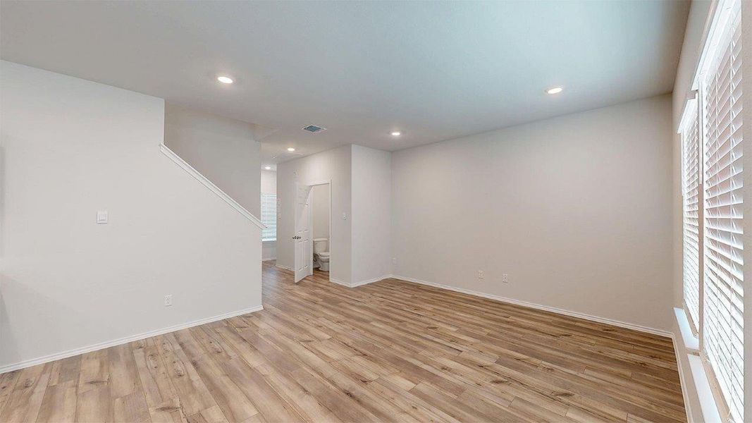 Open-concept living area featuring wood-finish flooring, recessed lighting, and a neutral color palette Open-concept living area featuring wood-finish flooring, recessed lighting, and a neutral color palette