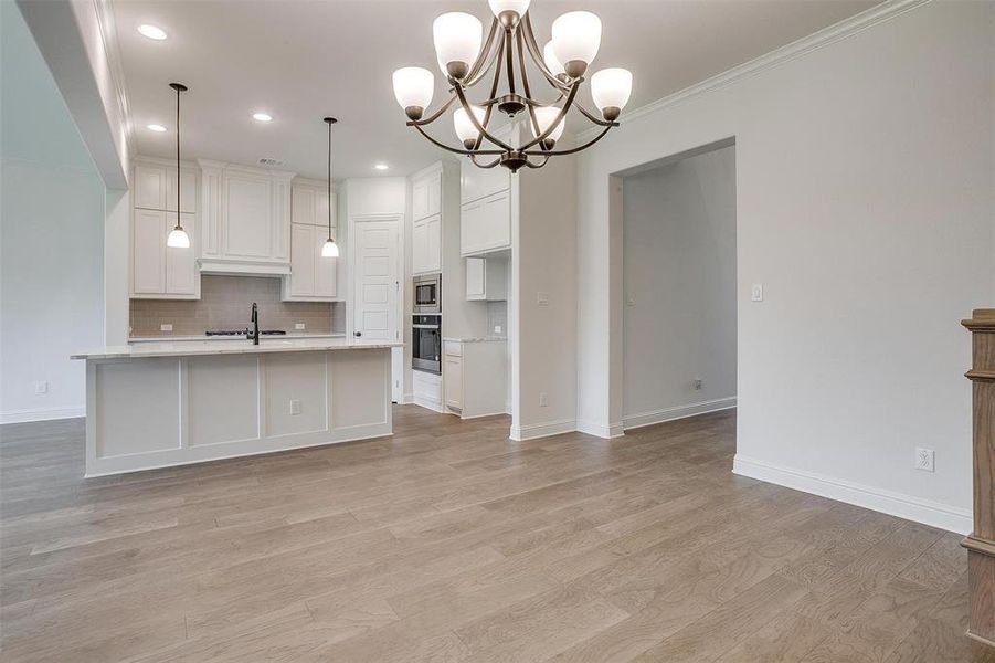 Kitchen featuring light hardwood / wood-style flooring, stainless steel appliances, tasteful backsplash, sink, and decorative light fixtures