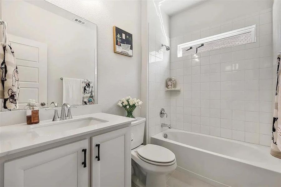 Full bathroom featuring toilet, vanity, and tiled shower / bath combo