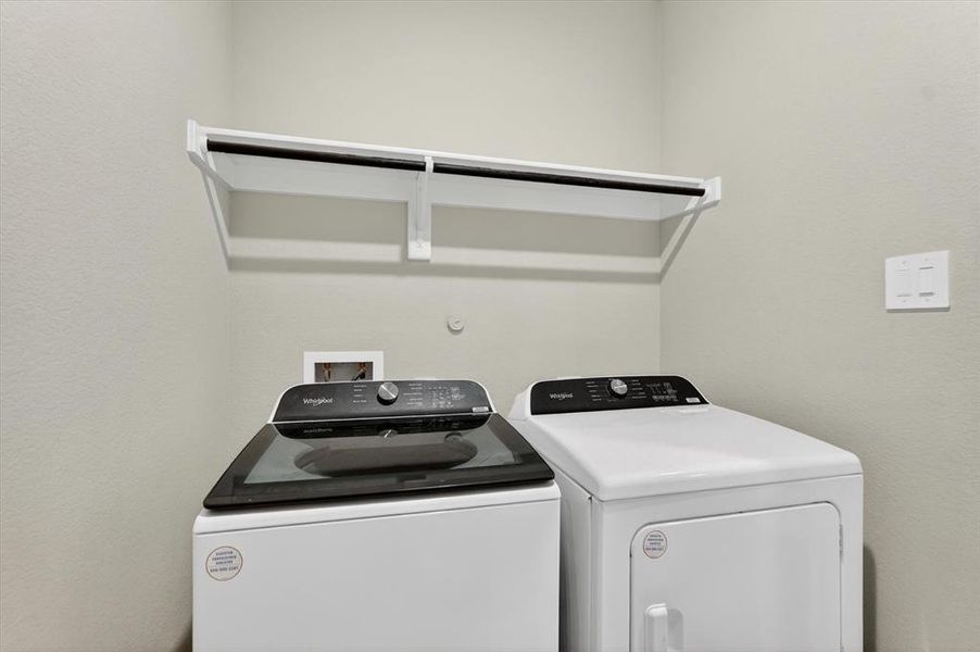 Dedicated laundry area featuring a white wall-mounted shelf with an integrated hanging rod Dedicated laundry area featuring a white wall-mounted shelf with an integrated hanging rod