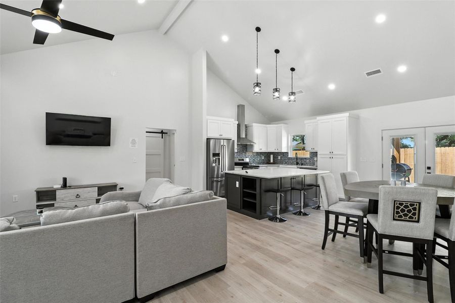 Living area with beamed ceiling, recessed lighting, light wood-type flooring, high vaulted ceiling, and french doors