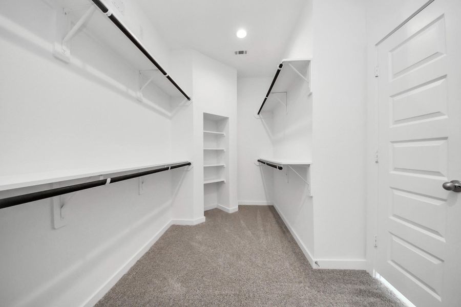 Walk-in closet that epitomizes luxury and practicality. This generously sized space features built-in shelving, offering abundant room for impeccable organization. High ceilings and recessed lighting create a bright and welcoming ambiance. Sample photo of completed home with similar floor plan. Actual colors and selections may vary. Walk-in closet that epitomizes luxury and practicality. This generously sized space features built-in shelving, offering abundant room for impeccable organization. High ceilings and recessed lighting create a bright and welcoming ambiance. Sample photo of completed home with similar floor plan. Actual colors and selections may vary.