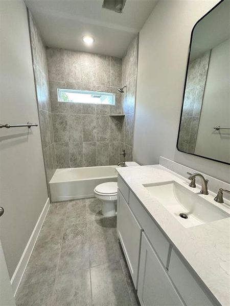 Full bathroom upstairs featuring oversized vanity, toilet, tile floors, and tiled shower / bath