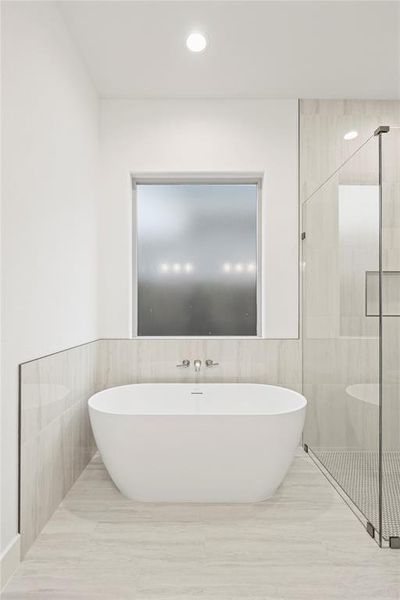 Full bath featuring tile walls, a shower stall, a soaking tub, and recessed lighting