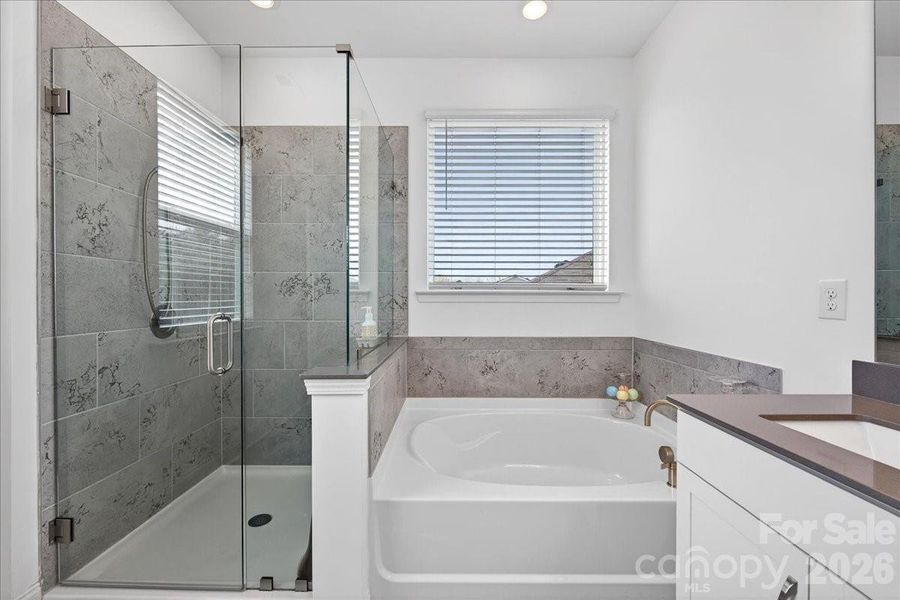 Elegant tile-surround shower with frameless glass shower doors and a large soaking tub as well.