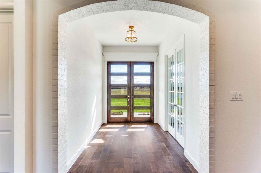 Entryway featuring french doors, wood finished floors, and arched walkways Entryway featuring french doors, wood finished floors, and arched walkways