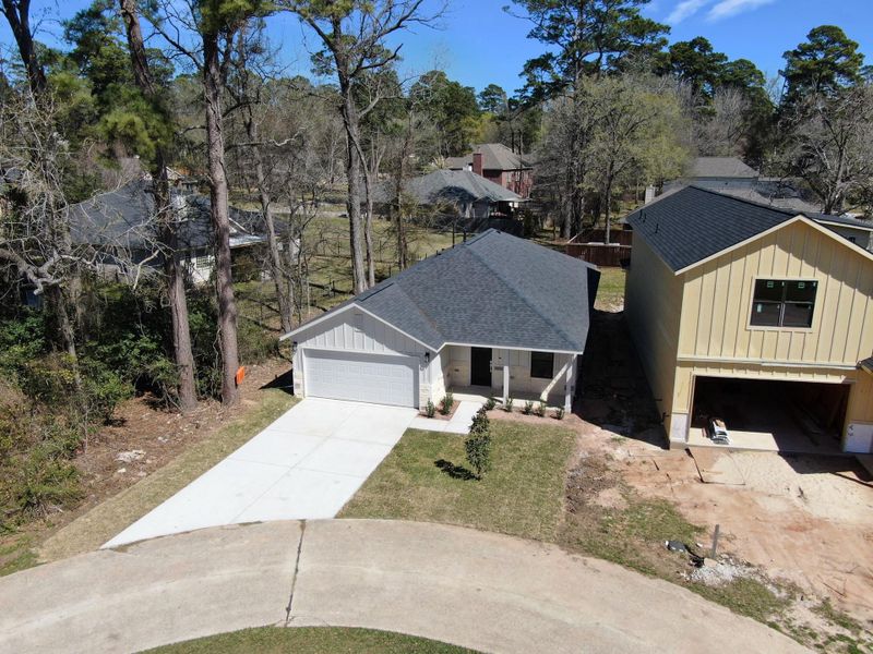 A stunning street-level aerial view showcasing the fresh, modern facade of this new construction. Highlights include the clean lines of the "board and batten" siding, a pristine concrete driveway, and professional xeriscaping that provides instant curb appeal.