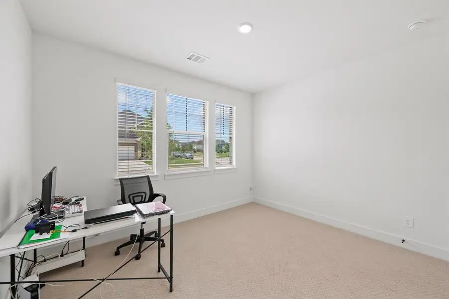 Bright room featuring multiple windows with horizontal blinds, neutral wall tones, recessed lighting, and carpet flooring Bright room featuring multiple windows with horizontal blinds, neutral wall tones, recessed lighting, and carpet flooring
