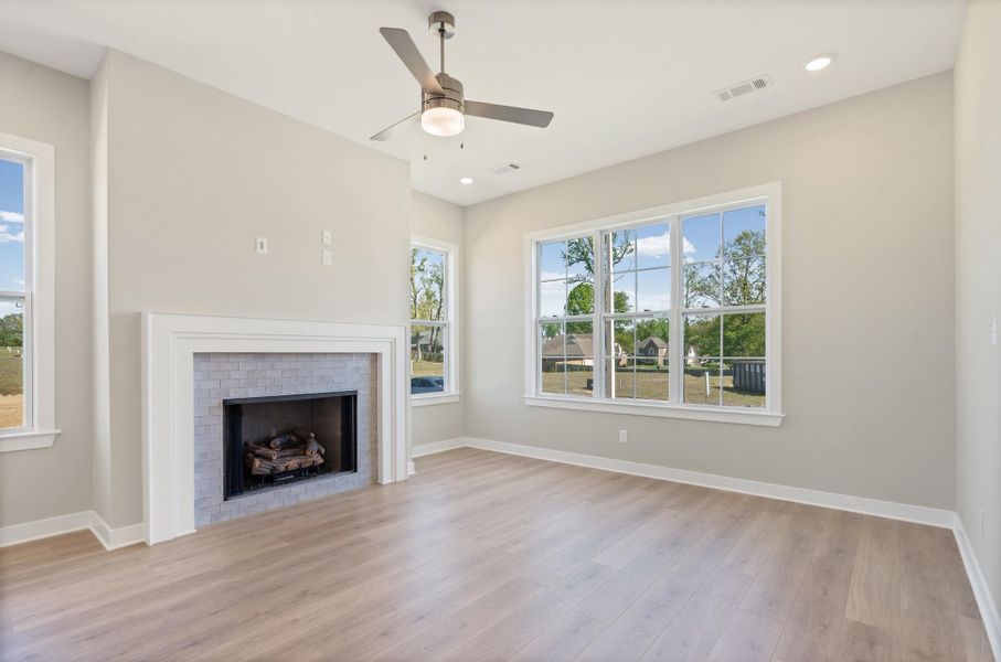 Unfurnished living room with ceiling fan, a brick fireplace, light wood-style flooring, and recessed lighting