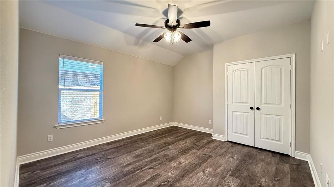 Unfurnished bedroom with dark hardwood / wood-style flooring, vaulted ceiling, a closet, and ceiling fan