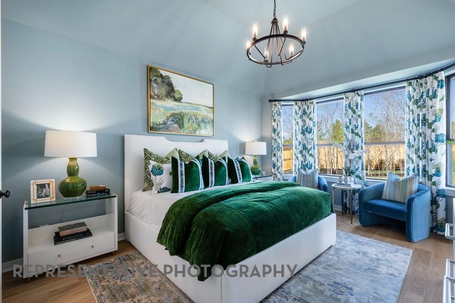 Bedroom featuring a chandelier, wood finished floors, and lofted ceiling Bedroom featuring a chandelier, wood finished floors, and lofted ceiling