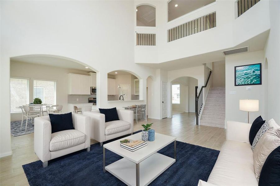 The open floor plan connects the kitchen seamlessly to the living area, perfect for modern lifestyles. Enjoy the beauty of arched doorways, sleek tile flooring, and the view of the upstairs balcony. Whether hosting guests or spending a quiet night in, this space is designed for comfort and function.