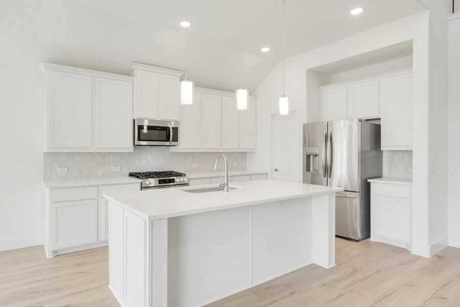 White kitchen with center island, stainless steel appliances, pendant lights, and light hardwood floors