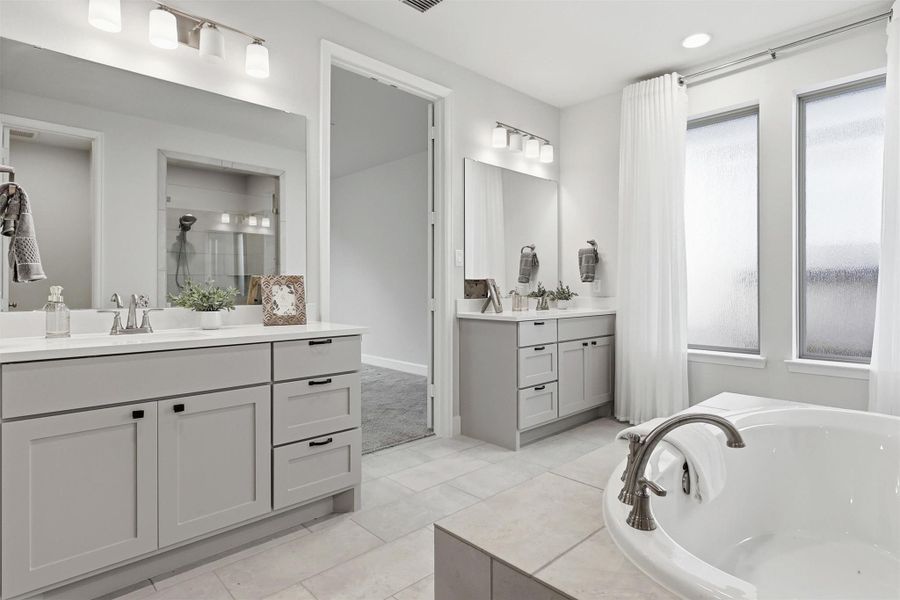 Separate vanities offer abundant storage, generous countertop space, and individual prep areas, making busy mornings effortless. Soft natural light, designer fixtures, and timeless finishes complete this elegant retreat.