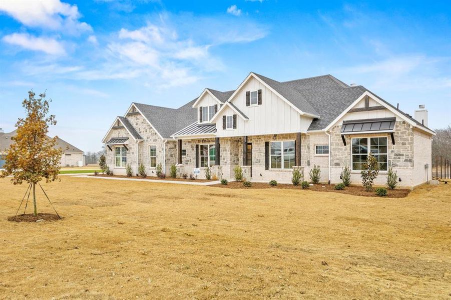 Modern inspired farmhouse featuring a standing seam roof, a porch, roof with shingles, stone siding, and board and batten siding Modern inspired farmhouse featuring a standing seam roof, a porch, roof with shingles, stone siding, and board and batten siding