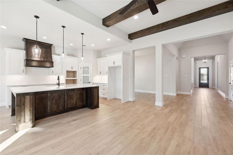 Kitchen featuring a large island, ceiling fan, sink, light hardwood / wood-style flooring, and pendant lighting