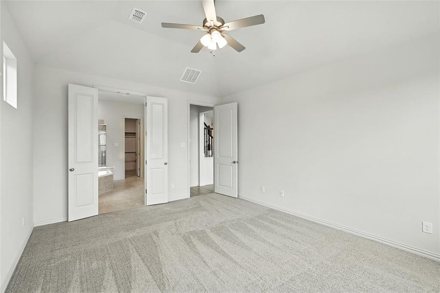 Unfurnished bedroom with light colored carpet, a ceiling fan, and lofted ceiling