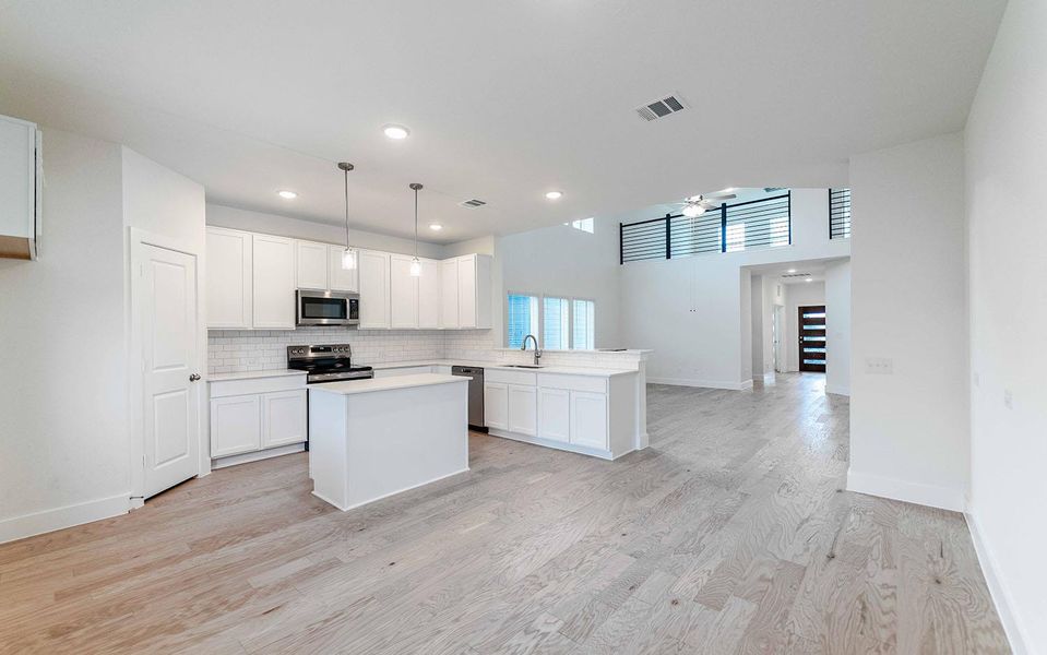 Kitchen featuring a kitchen island, white cabinets, a peninsula, stainless steel appliances, and light wood-type flooring Kitchen featuring a kitchen island, white cabinets, a peninsula, stainless steel appliances, and light wood-type flooring