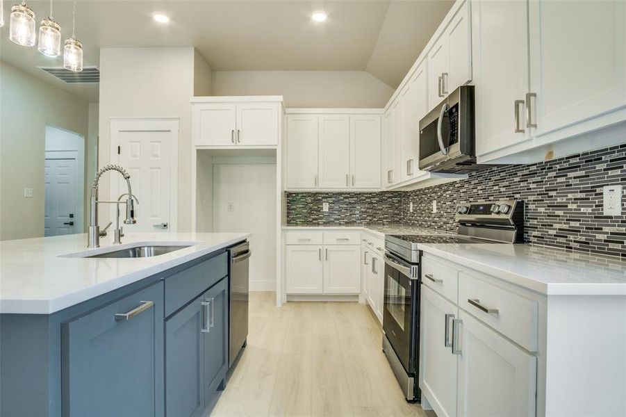 Kitchen featuring white cabinets, appliances with stainless steel finishes, a sink, and light wood-style flooring